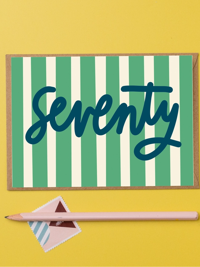 A 70th birthday card featuring the word seventy in navy writing on a green and cream striped background.