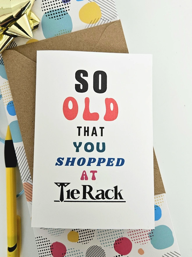 A photograph of the front of a humorous A6 greeting card illustrated using brightly coloured text and the retro shop logo. The text says so old you shopped at Tie Rack