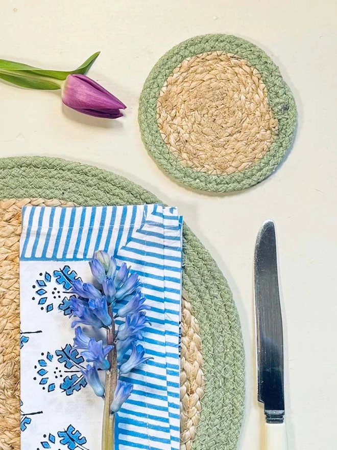 Seagrass coaster with olive rings, shown on a light surface with tulip. 