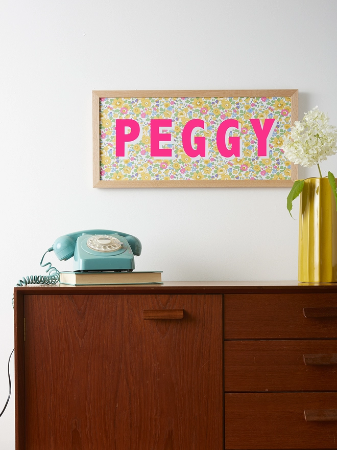 Personalised framed word/name picture in neon pink with white highlights on Liberty Betsy yellow fabric
