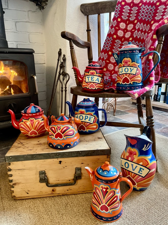 Orange coffee pot pictured alongside the rest of the enamelware collection