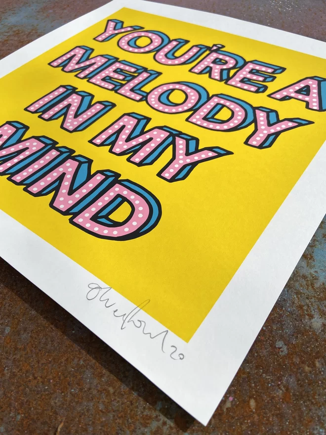 "Melody In My Mind" Hand Pulled Screen Print  square on yellow back ground with hand written letters in pink with dots printed on top that say melody of my mind 