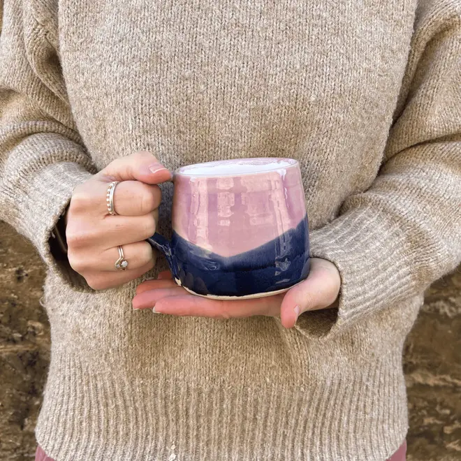 Landscape Large Round Mug, a person in a jumper holding a colourful coffee mug in front of them. 