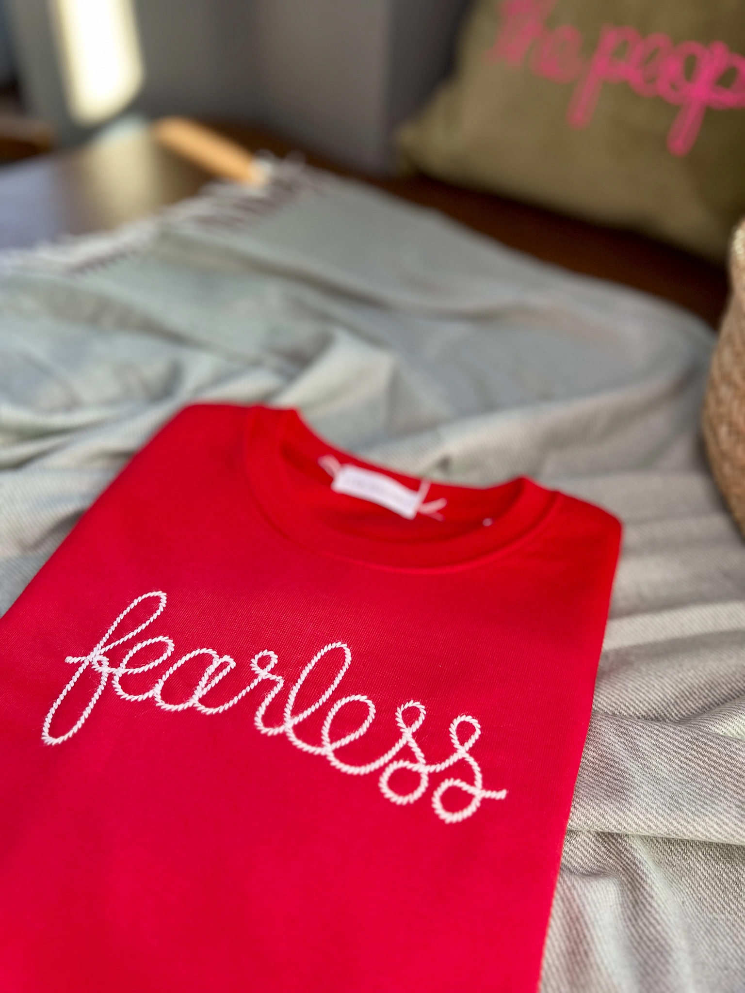 A red folded sweatshirt embroidered with the word fearless