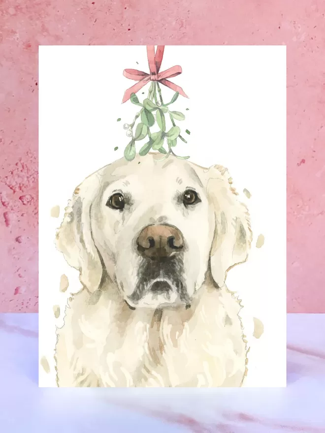 A Christmas card featuring a hand painted design of a Cream Golden Retriever, stood upright on a marble surface.