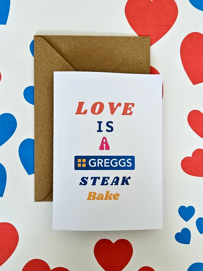  A photograph of the front of a humorous A6 greeting card illustrated using brightly coloured text. The text says love is a Greggs steak bake