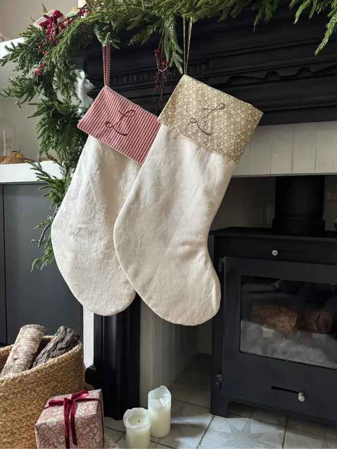 Striped Embroidered Christmas Stocking. A Green floral and a red and beige striped cuffed stocking hung on a mantle