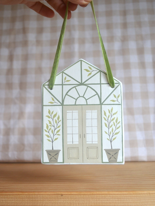 white ceramic hanging decoration with green and brown greenhouse illustration design