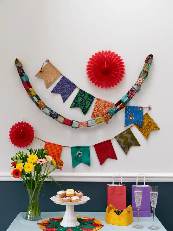 Colourful decorations against a wall behind a table of cupcakes