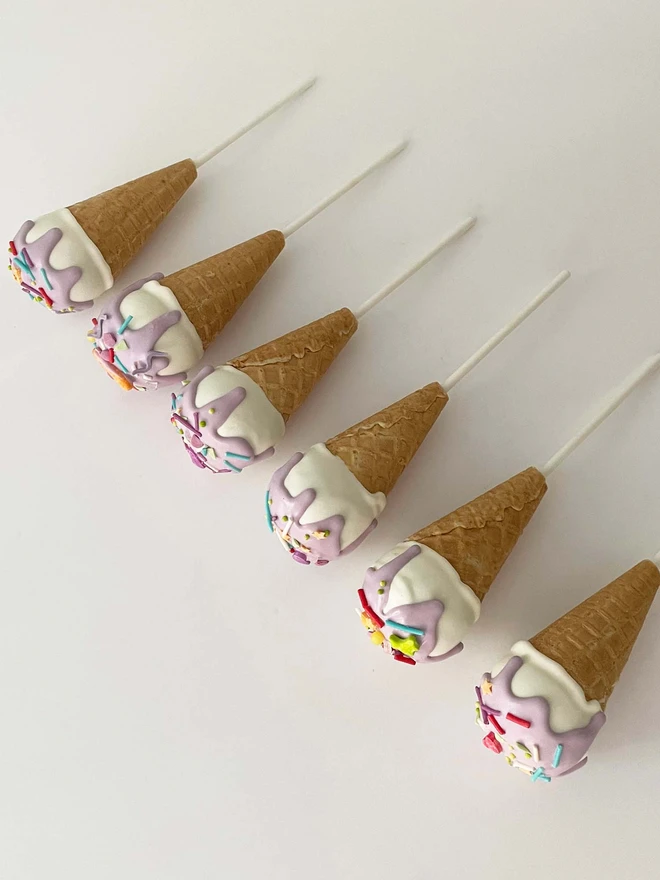 Ice Cream Cake Pops (Pack Of 6, 12, 18, 24), ice cream cake pops placed in a row against a plain surface. 