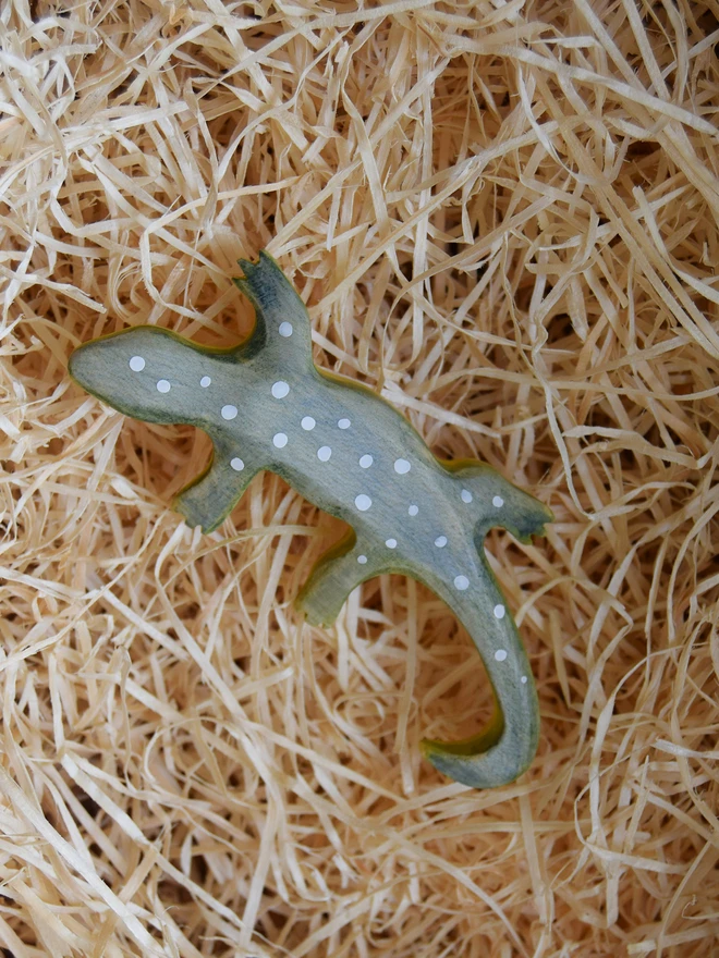 wooden toy gecko lizard in woodwool