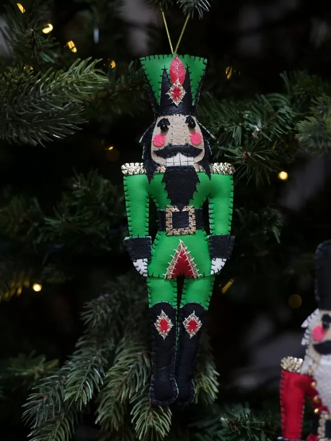 Hetty and Dave green leatherette hand stitched nutcracker decoration hanging on a Christmas tree