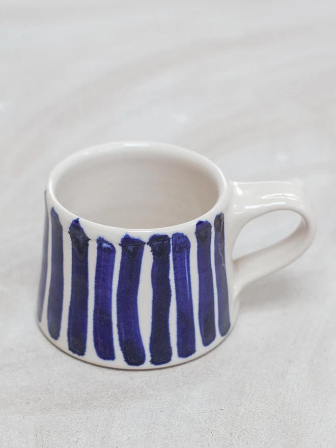 Gloss handmade mug with cobalt blue hand-painted stripes, close up
