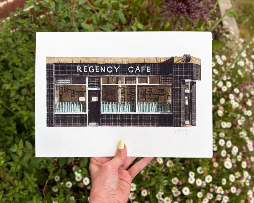 Pimlico Regency Cafe Giclée Print (Unframed) Victoria, a print of a cafe held by a person in front of some flowers. 