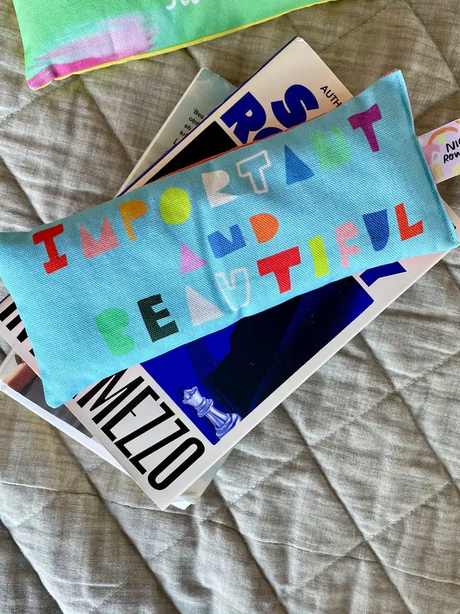 Brightly coloured lavender eye pillow atop a pile of books