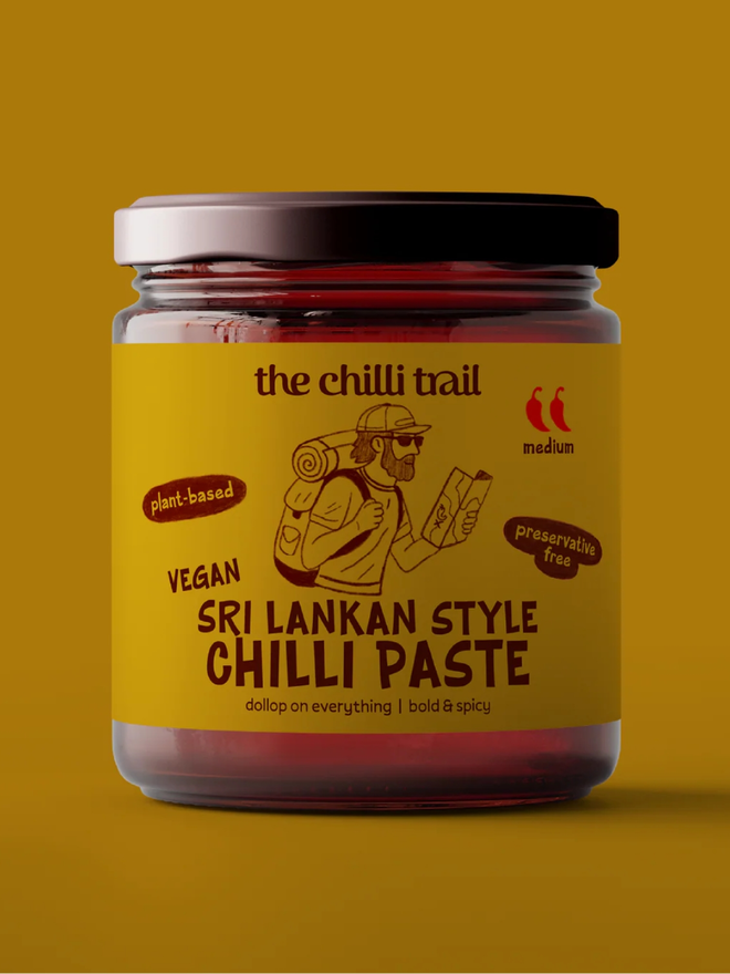 sri lankan style vegan chilli paste. a jar of chilli paste photographed against a mustard yellow background.