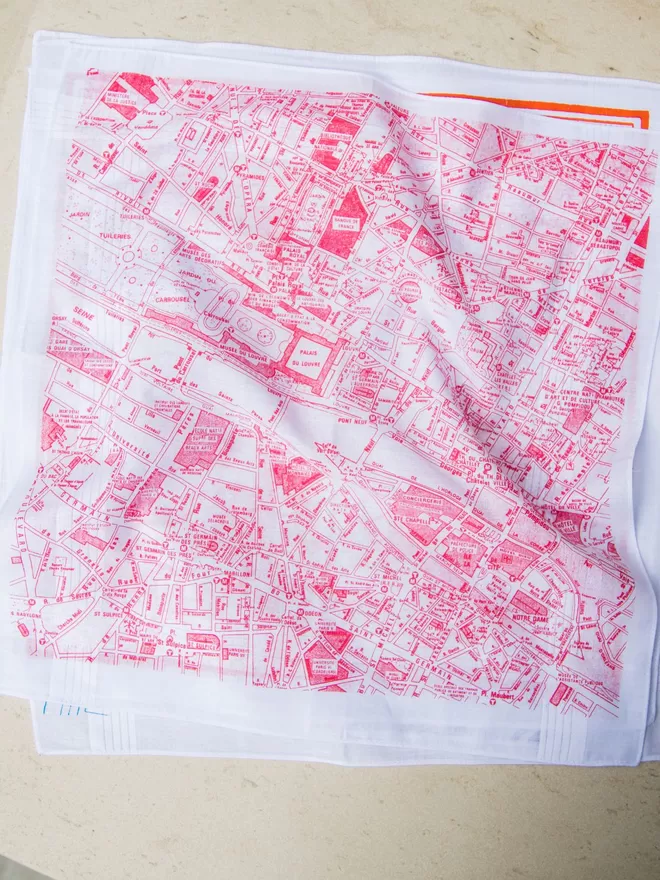 A pile of Mr.PS printed map hankies with a Paris hankie printed in coral on the top