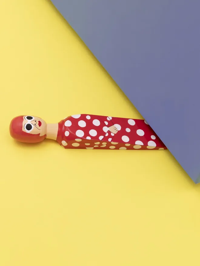 Wooden Door Stopper (Yayoy Red Polka Outfit), a colourful wooden door stop sitting under a door.