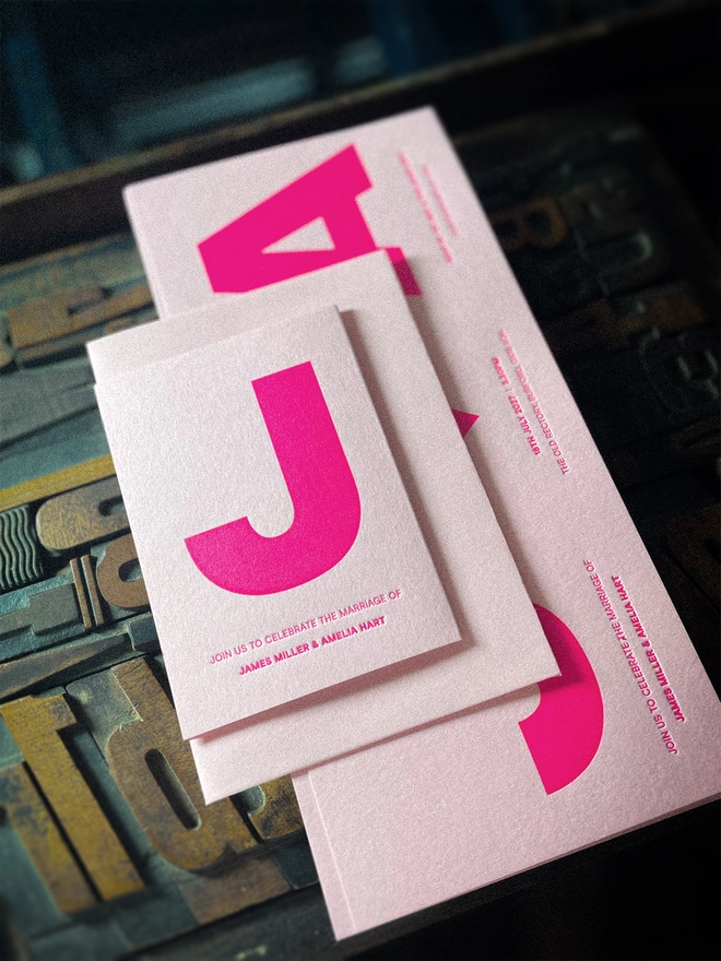Contemporary made-to-order letterpress wedding stationery with bold fluorescent pink typography and heart, personalised for the couple and printed on premium GF Smith Colorplan card.