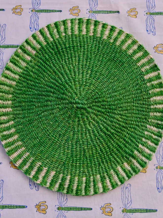 Green placemat sitting on a patterned tablecloth