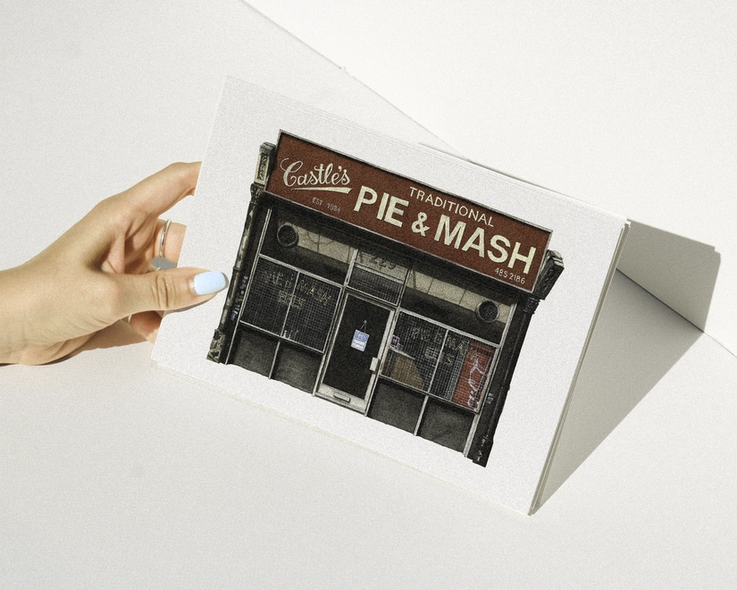 A hand with blue nail polish holding a print featuring an illustration of Castle’s Traditional Pie & Mash shop against a white background.