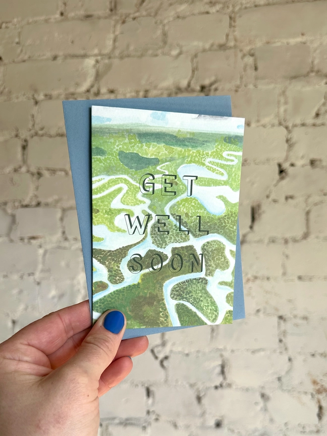 a greetings card featuring an illustration of the Everglades National Park with the text “GET WELL SOON” with a blue envelope