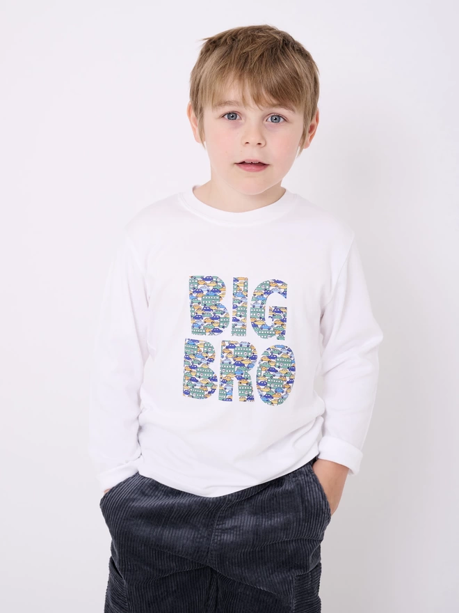 Big Bro appliquéd in a vintage cars Liberty print on a white cotton long sleeve t-shirt. Worn by a smiling 5 year old boy.