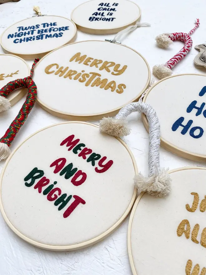 custom phrase embroidered christmas hoop. cotton hoop embroidered with assorted festive phrases.