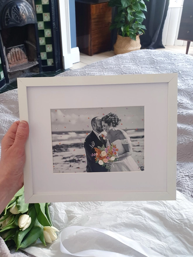 Wedding photo with hand embroidered bouquet and confetti held in white frame