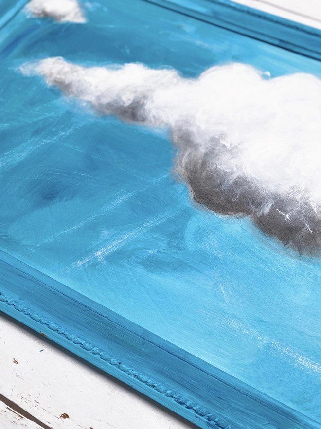 large cloud painting in turquoise painted directly onto a frame