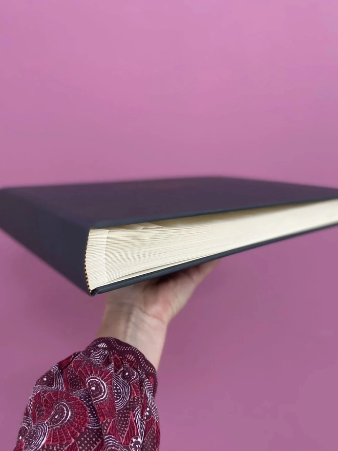 Bold & Beautiful Personalised Guest Book, woman holding guest book against a purple background. 