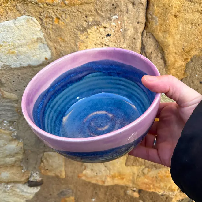 Landscape Ramen Bowl, a colourful ramen bowl held in front of a brick backdrop. 