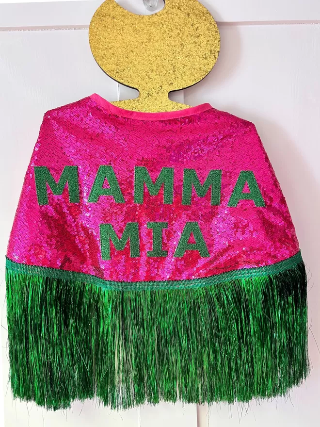 a midi cape with hot pink sequins, green text reading 'MAMMA MIA' and green tinsel