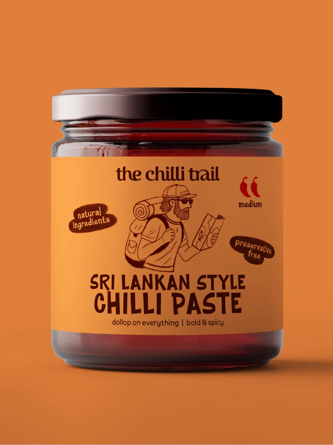 sri lankan style chilli paste. a jar of chilli paste photographed against an orange background.