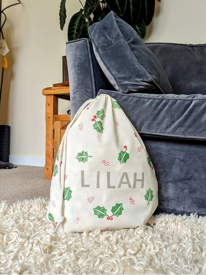 personalised drawstring christmas sack. a drawstring bag with printed christmas motifs and a personalised name.