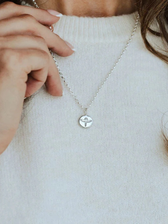 A woman wearing Sterling silver Phoenix Pebble Necklace against a white jumper