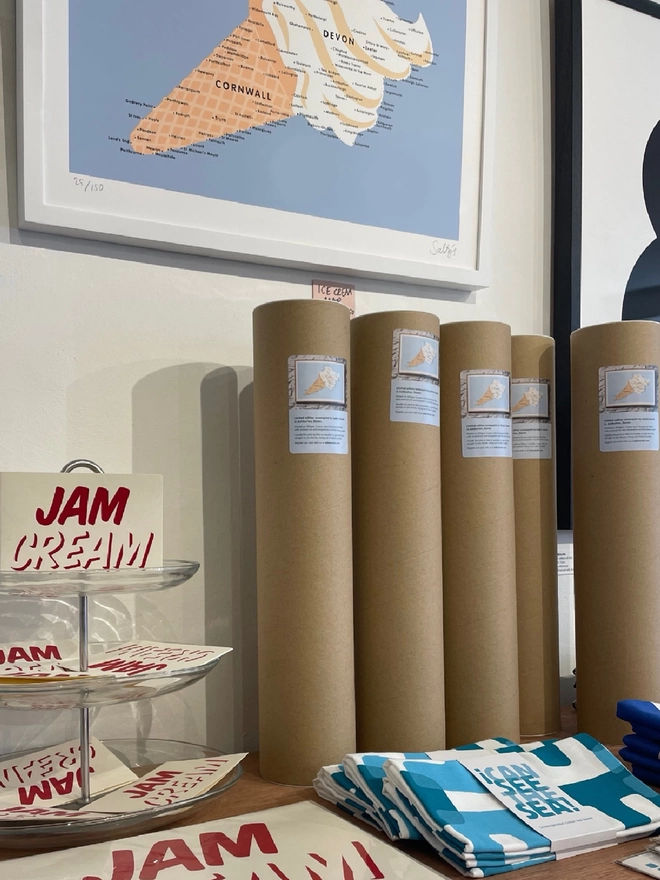In Salty’s Studio shop, the Ice Cream Map print is hung on the wall in a white frame, the tubes of prints are stood underneath together with colourful turquoise teatowels and Cream First cards. 