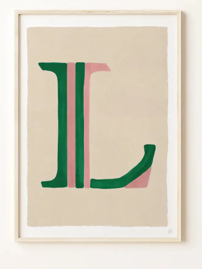 Framed wall art print featuring a large decorative letter “L” in humbug stripes
centered on a white background. 