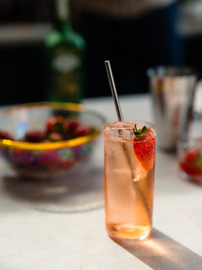 Glass filled with Holly's Strawberry Spirit, Tonic Water and a fresh Strawberry