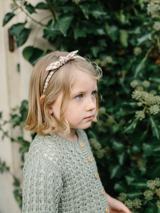 Little girl in her rust alice band in gingham