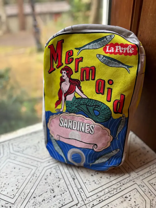 Mermaid Tin Cushion, a decorated mermaid cushion sitting on a window sill. 
