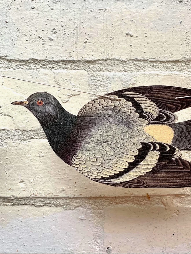 Close up of a paper cutout pigeon against a brick wall