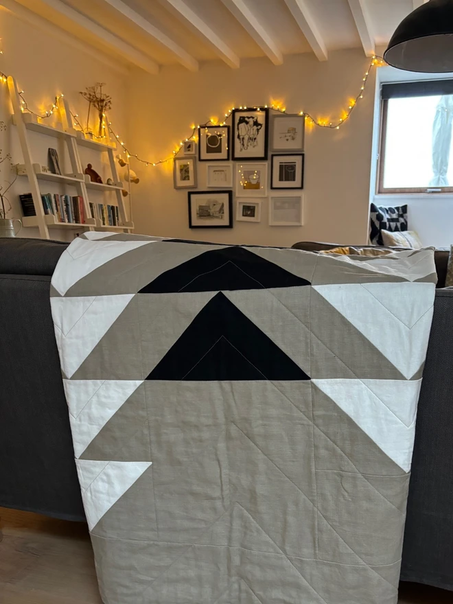 Flow Taupe Linen Throw Quilt with black & white triangle detail. Throw quilt folded over sofa.