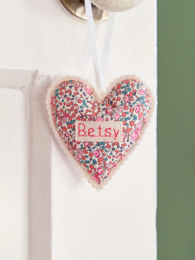 Personalised hanging heart decoration in liberty print - hanging on a door handle on a white door with green walls