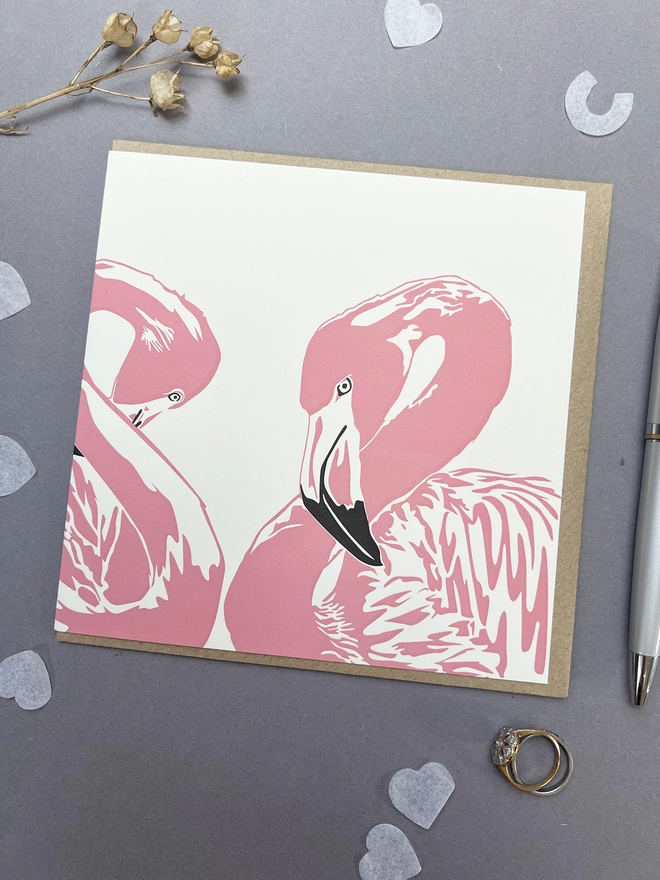 This gorgeous letterpress greeting card depicts two flamingos, one shyly hiding its head, making a love heart shape with their necks