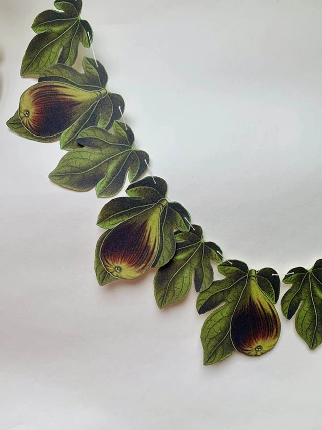 A length of bunting featuring figs and fig leaves in greens and browns