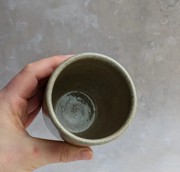 Birds eye view biscuit coloured croissant coffee cup with a subtle croissant design, placed against a grey marble background.