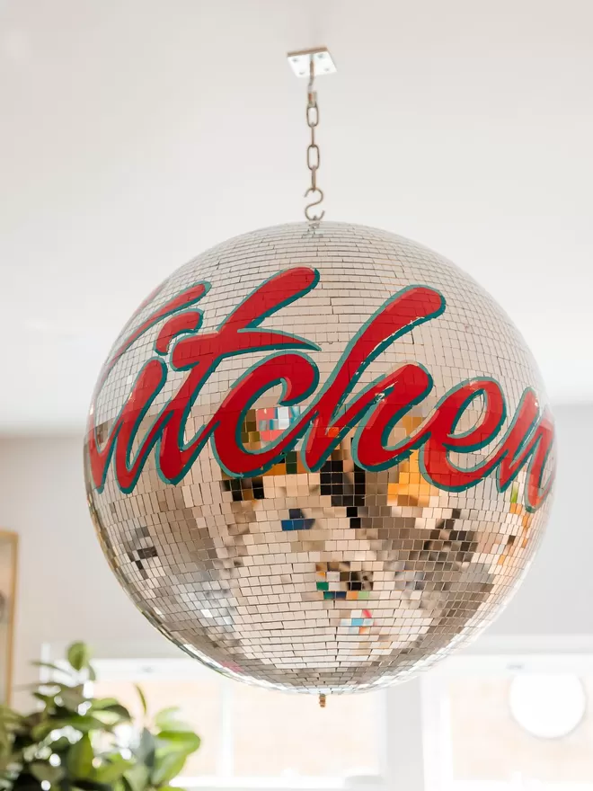 Third Eye Kitchen Disco disco ball with dancing queen written in red around the ball seen in a kitchen.