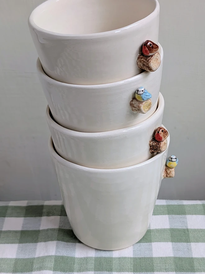 robin and blue tit espresso coffee cups with a tiny handmade bird resting on a small ceramic wooden tree branch in white earthenware pottery