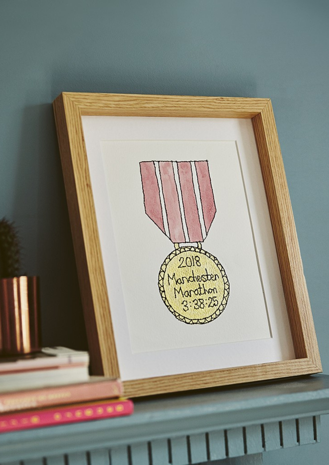 A hand painted and embroidered gold medal artwork with a pink ribbon personalised with a marathon achievement